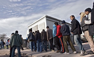 Des migrants attendent la distribution des repas sur le port de Calais (illustration).
