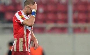 Pajtim Kasami, milieu de terrain de l'Olympiakos, effondré après la défaite de son équipe face aux Ukrainiens de Dniepropetrovsk, le 26 février 2015. / AFP PHOTO / Aris Messinis