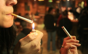 Une jeune femme allume sa cigarette avec un briquet (image d'illustration).