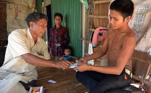 Le médecin sans diplôme Ken Mon (g) donne un médicament à un de ses patients, le 27 février 2015 à Kampong Speu, au Cambodge