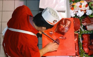 Un boucher découpe une piéce de boeuf au rayon boucherie d'un Intermarché, de Chalonnes-sur-Loire, en décembre 2004