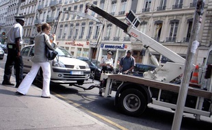 Des policiers municipaux procèdent à l'enlèvement d'une voiture par la fourrière, le 13 juillet 2006 dans le centre-ville de Lyon.