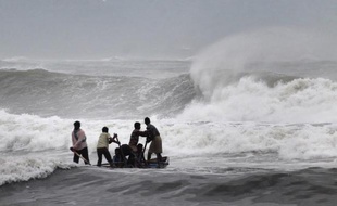 Des pêcheurs indiens tentent de sortir leur barque des fortes vagues le 11 octobre 2014 à Visakhapatnam alors que le cyclone Hudhud arrive sur les côtes de l'Inde