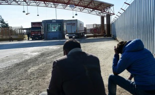 Deux personnes attendent qu'un camion entrant en Syrie revienne au poste frontière d'Oncupinar, près de Kilis en Turquie, le 9 février 2016