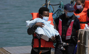 Un homme et un enfant migrants débarquent d'un navire des forces frontalières britanniques à Douvres, dans le sud-est de l'Angleterre, le jeudi 22 juillet 2021.