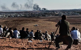 Des Kurdes regardent la fumée au-dessus de la ville de Kobané lors de frappes aériennes de la coalition, depuis une colline à Mursitpinar, le 15 octobre 2014, à la frontière syro-turque