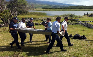 Des policiers transportent le débris appartenant peut-être à l'avion MH370 retrouvé sur une plage de Saint-André, à la Réunion, le 29 juillet 2015.