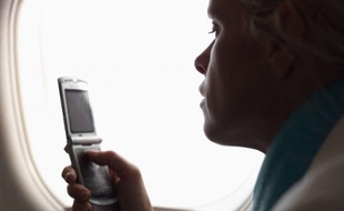 Un passager utilise son téléphone dans un avion.