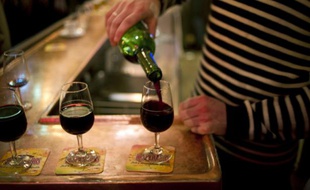 Un serveur remplit des verres de vin rouge sur le comptoir d'un bar de Paris, le 2 décembre 2011.
