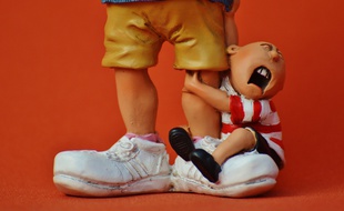 Figurine d'un enfant pleurant accroché aux pieds de sa baby-sitter. Illustration.