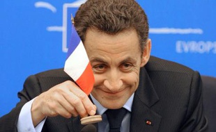 Nicolas Sarkozy, alors président de l'Union européenne, joue avec un drapeau français lors d'une conférence de presse au Conseil européen de Strasbourg, le 16 décembre 2008.