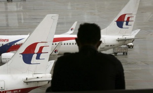 Un homme regarde des avions de Malaysia Airlines à l'aéroport de Kuala Lumpur, en Malaisie, le 27 mai 2014.