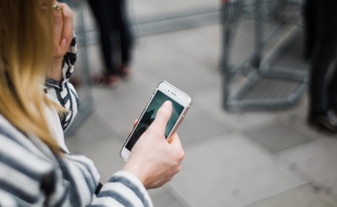 Une femme marchant dans la rue en utilisant son smartphone (illustration).
