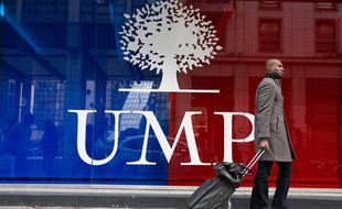 Photo d'illustration: Un homme passe devant un logo de l'UMP à Paris.