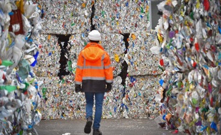 Un employé d'un centre de tri des Côtes-d'Armor marche entre les balles de déchets plastiques en attente d'être recyclés.