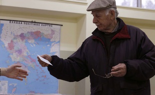 Un électeur tend son bulletin de vote dans un bureau d'Athènes, le 25 janvier 2015.