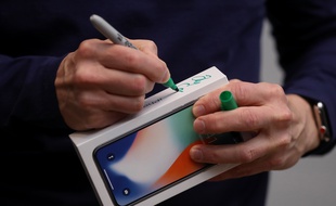 PALO ALTO, CA - NOVEMBER 03: Apple CEO Tim Cook signs the box of a new iPhone X at an Apple Store on November 3, 2017 in Palo Alto, California. The highly anticipated iPhone X went on sale around the world today. Justin Sullivan/Getty Images/AFP