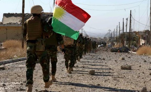 Des combattants kurdes et de la communauté Yazidie entrent avec un drapeau kurde dans la ville de Sinjar, au nord de l'Irak, reprise au groupe de l'Etat islamique (EI), le 13 novembre 2015