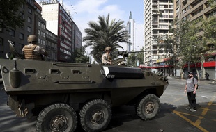 Un manifestant se tient face à un véhicule de l'armée dans les rues de Santiago du Chili, le 19 octobre 2019.