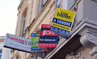 Des panneaux d'agences immobilières sur la façade d'un immeuble où un appartement est à vendre