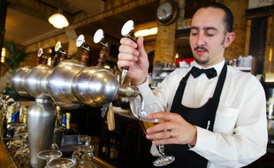 Un garçon de café remplit un verre de bière