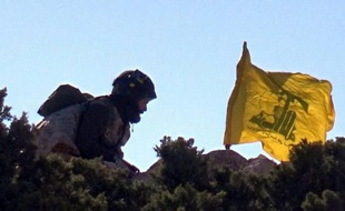 Photo fournie par le service de presse du Hezbollah en mai 2015 d'un combattant du Hezbollah érigeant le drapeau du mouvement en Syrie près de Qalamun.