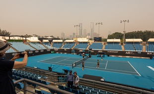 Un court de tennis du Melbourne Park où se déroule l'Open d'Australie, le 15 janvier 2020, avec les grattes-ciel de Melbourne couverts par le smog de la fumée des incendies.