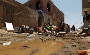 Des yéménites observent le 31 mars 2015 près de l'aéroport de Sanaa des maisons détruites par les bombardements aériens de la coalition dirigée par l'Arabie saoudite contre les milices chiites houthies