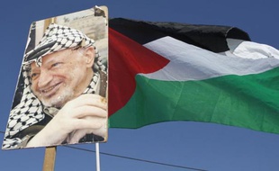 Portrait de Yasser Arafat sous un drapeau palestinien près de Bethléem dans les Territoires palestiniens, le 11 novembre 2011