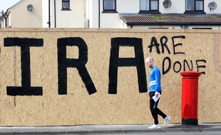 Un homme marche devant un graffiti «C'en est fini de l'IRA» à Londonderry, le 20 avril 2019.