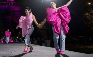 Women parade on a runway in front of the Eiffel Tower lightened in pink to mark the Breast Cancer Awareness Month, an annual campaign to raise awareness about the impact of breast cancer, in Paris on October 1, 2021. (Photo by Thomas SAMSON / AFP)