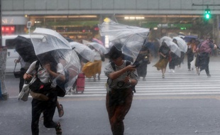 A Tokyo, des passants se protègent des pluies torrentielles du typhon Jongdari, le 28 juillet dernier.