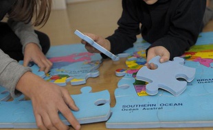 Des enfants jouent avec un tapis-puzzle, le 12 décembre 2010.