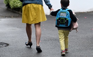Un enfant tient la main d'un adulte (photo d'illustration)