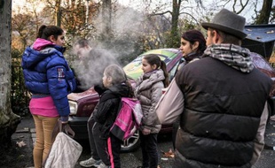 Des membres de familles sans-abri dont les enfants vont à l'école se tiennent près de leur voiture à Lyon le 27 novembre 2014