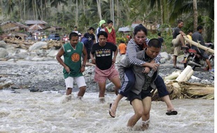 Des Philippins traversent une rivière à New bataan, le 5 décembre 2012, après le passage du typhon Bopha
