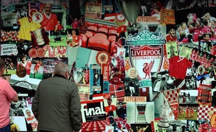 Un homme observe le collage de photographies qui orne la boutique du Liverpool FC