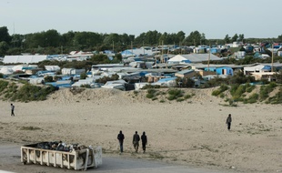 Des migrants marchent près de la « jungle » de Calais, le 26 juillet 2016