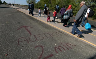 Des migrants passent près d'un message "Autriche-2 minutes", écrit au sol à la frontière austro-hongroise, près de Nickelsdorf, du côté autrichien, le 12 septembre 2015