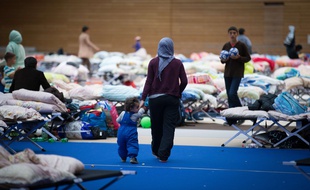 Des migrants dorment dans la hall d'un parc olympique à Berlin le 12 septembre 2015.