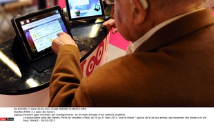 Une personne âgée demande des renseignements sur une tablette simplifiée lors du 14e Salon des seniors, le 30 mars 2012.
