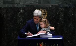 Le secrétaire d'Etat américain John Kerry signe l'accord sur le climat tenant sa petite-fille, à l'ONU à New York, le 22 avril 2016