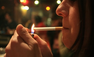 Une femme allumant une cigarette.