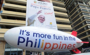 Un poster géant et un ballon gonflable célébrent la venue du pape François aux Philippines, le 10 janvier 2015 dans une rue de Manille