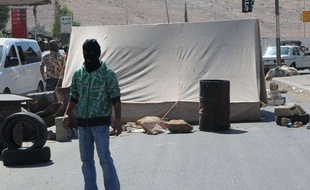 Un homme masqué appartenant à un groupe sunnite, bloque une route à la frontière libano-syrienne, à Masnaa, dans l'Est du Liban, le jeudi 16 août 2012