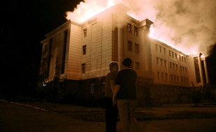 Bystanders watch a fire consuming a school in downtown Donetsk on August 27, 2014, after being hit by a shelling. Several civilians died when their car was completely burned after being hit by shell fragments in central Donetsk, the rebel-held city in eastern Ukraine. AFP PHOTO/ FRANCISCO LEONG