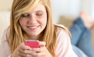 Illustration: une jeune fille regarde son smartphone.