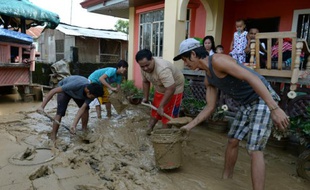Les habitants enlèvent la boue le 20 octobre 2015 dans les rues de Cabanatuan City, au nord de Manille, apportée par les fortes pluies occasionnées par le typhon Koppu qui a fait au moins 22 morts