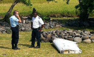 Un policier et un gendarme près du débris d'avion retrouvé à la Réunion, le 29 juillet 2015.