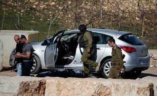 Des soldats israéliens contrôlent le 11 décembre 2015 la voiture d'un Palestinien, abattu dans une tentative d'attaque anti-israélienne à la voiture-bélier au check-point de Halhul, au nord de Hébron, en Cisjordanie
